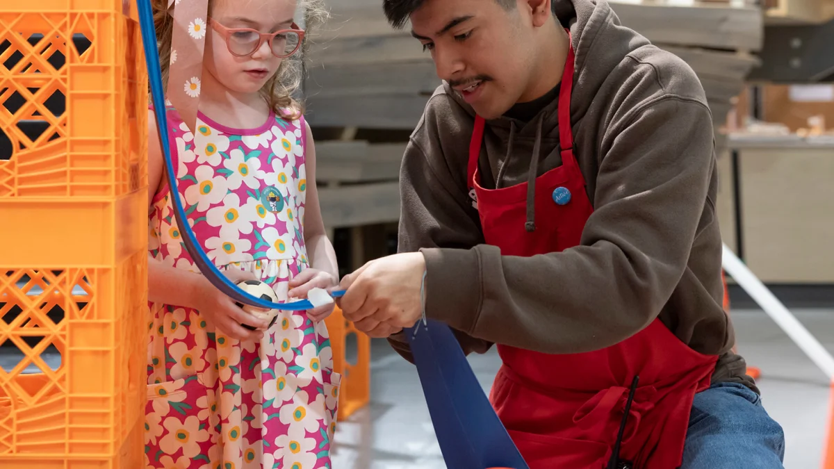 Senior Explainer guiding a young visitor through a NYSCI exhibit